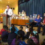 Houston Federation of Teachers President Zeph Capo addresses students and faculty to kick off a First Book distribution in Houston. Seated are AFT President Randi Weingarten and Houston ISD Superintendent Richard Carranza.