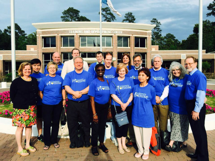 Group photo of A-F-T Lone Star College members in matching blue shirts standing outside of an administration building