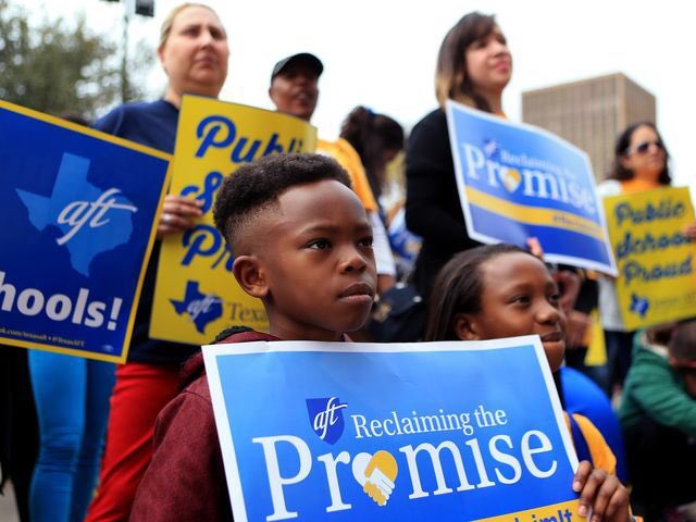 Child stands in front of activists with sign that reads: "AFT: Reclaiming the Promise."