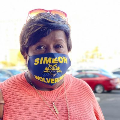Photo of Vanessa Betts in a parking lot, wearing a "Simeon Wolverines" face mask.