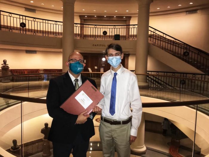Representative Jon Rosenthal and Riley Schaudel pose together near the Capitol rotunda. They are both wearing face masks.