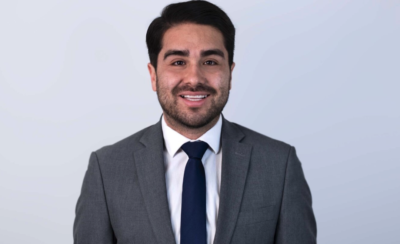 Photo of Joshua Acevedo, wearing a suit and smiling.